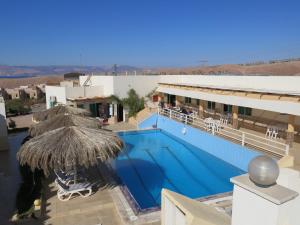 a large swimming pool with a straw umbrella next to a building at Red Sea Dive Center in Aqaba