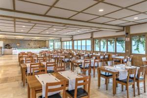 ein Esszimmer mit Holztischen und Stühlen in der Unterkunft Troas Beach Hotel in Tavaklı