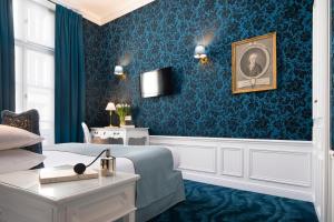 uma sala de estar com uma cama e uma parede azul em Odeon Hotel by Malone em Paris