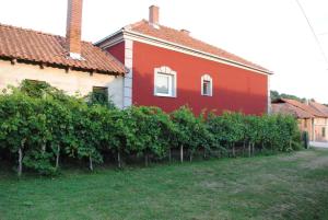 een rood huis met een heg druiven bij Vila Happy Story in Knjazevac.