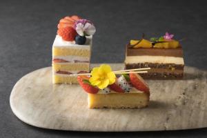 three cakes on a cutting board with fruit on top at Sheraton Okinawa Sunmarina Resort in Onna