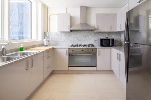 uma cozinha com armários brancos e um frigorífico de aço inoxidável em Frank Porter - Mon Reve no Dubai