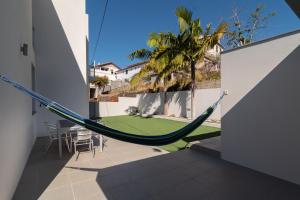 a hammock in the middle of a house with a lawn at Luxo & Conforto in Calheta