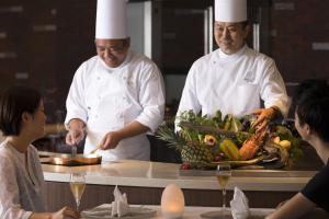a chef preparing food in a kitchen with a group of people at Sheraton Okinawa Sunmarina Resort in Onna