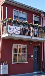 ein rotes Gebäude mit einem Balkon mit Blumen darauf in der Unterkunft La Riviera in Loreo