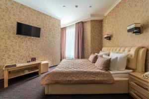 Habitación de hotel con cama y TV en la pared en Kravt Sadovaya Hotel, en San Petersburgo