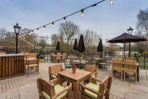 un patio al aire libre con mesas, sillas y luces en The Bridge Hotel en Chertsey