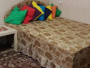 クルガンにあるMaxim Gorky Apartmentsのベッド(カラフルな枕付)