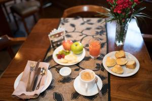 una mesa con platos de comida y un jarrón de flores en Hotel Boutique La Posada, en Sucre