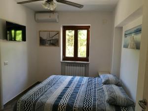 una camera da letto con un letto con un piumone blu e una finestra di Edvige'S House a San Felice Circeo