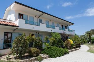 uma casa branca com janelas azuis e arbustos em Hotel Residence La Ventola em Vada