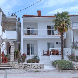 una casa blanca con una palmera delante de ella en Holiday Home Rosemary, en Klek