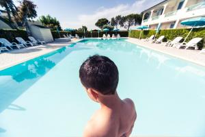 a young boy standing in a swimming pool at Hotel Residence La Ventola in Vada