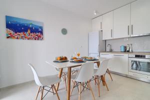 eine weiße Küche mit einem Tisch und Stühlen in der Unterkunft Holiday Home Rosemary in Klek