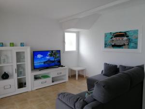 sala de estar con sofá y TV de pantalla plana en VILLA PIÑUELO (RELAX EN EL PARAÍSO)., en Es Mercadal