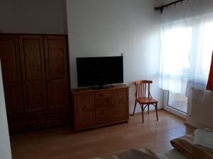 a living room with a tv on a cabinet and a chair at Rózsakert Apartmanház in Hajdúszoboszló