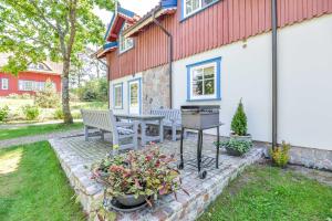 a patio with two benches and a grill in front of a house at Apartamentai Geliu Vila in Nida