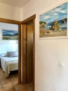 1 dormitorio con 1 cama y una pintura en la pared en Apartamento Triana II Bolonia, Tarifa en Bolonia