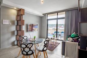 uma sala de estar com uma mesa e cadeiras e uma televisão em Inner Harbour Charm em Durban