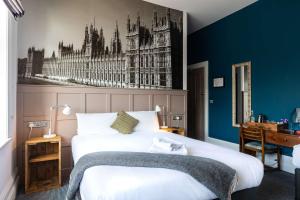 een slaapkamer met een groot bed en een bureau bij The Station Hotel in Londen