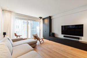 uma sala de estar com um sofá e uma televisão de ecrã plano em Hyper-Luxeappartement, zeezicht, centrum, airco, optie hotelservices em Ostend