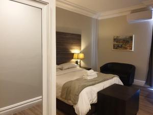 ein Schlafzimmer mit einem Bett, einem Stuhl und einem Spiegel in der Unterkunft Andaluz Boutique Hotel in Durban