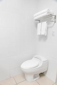 a white toilet in a white bathroom with towels at Costa del Sol Wyndham Pucallpa in Pucallpa