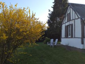 two chairs sitting in the yard of a house at La petite maison normande in Ticheville