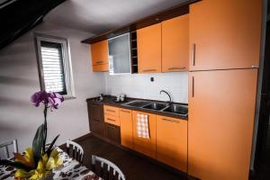 una cucina con armadi arancioni, lavandino e tavolo di Villini Frutteto a Castellaneta Marina