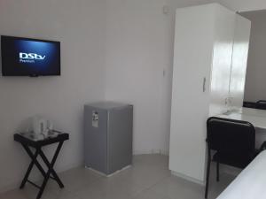 Habitación con nevera pequeña y TV en la pared. en Rest & Digest en Serowe