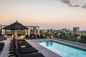 a pool on the roof of a building with lounge chairs and an umbrella at Kimpton Everly Hotel Hollywood by IHG in Los Angeles