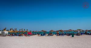 a group of people sitting on a beach with umbrellas at La Frontiera in Vama Veche