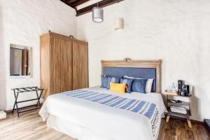 a bedroom with a large bed with blue and yellow pillows at Hotel Milagro, Puebla Centro in Puebla +21 photos
