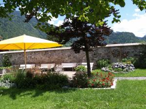 a patio with a yellow umbrella and tables and chairs at Seminar- und Gästehaus im Kloster Bezau in Bezau