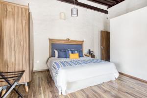 a bedroom with a bed with blue and yellow pillows at Hotel Milagro, Puebla Centro in Puebla