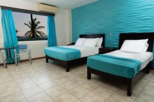 1 dormitorio con 2 camas y pared azul en Hotel Puntarenas Beach en Puntarenas