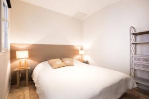 una camera con un letto bianco e due lampade di Beau T3 *** pour 2 à 4 pers avec patio privatif a La Couarde-sur-Mer