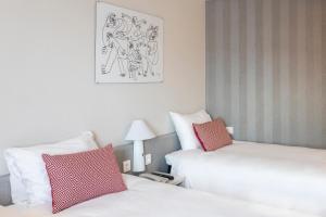 duas camas num quarto de hotel com almofadas vermelhas e brancas em Ibis Valencia Alfafar em Alfafar