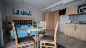 1 dormitorio con 1 cama, mesa y sillas en Tramontana Family & Wellness, en Darłówko