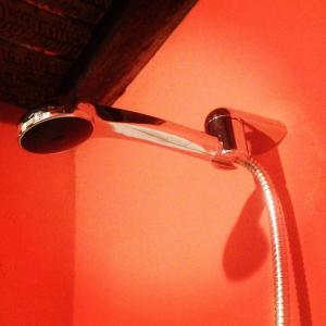a shower head in a bathroom with a red wall at Hotel Ika Mirador Suesca in Suesca