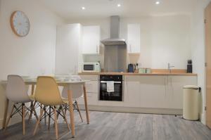 a kitchen with white cabinets and a table and chairs at Book our Royal Suite today! Elegant spacious 2 bed apartment in the city centre - perfect for work or leisure! in Sheffield