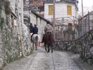 Duas pessoas a andar a cavalo num beco de pedra. em Agriogido - Rupicapra Villas em Papigko