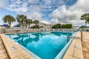 a swimming pool with blue water and palm trees at Shoreline Towers in Destin