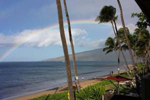 einen Regenbogen über einem Strand mit Palmen und dem Meer in der Unterkunft Kihei Kai Oceanfront Condos in Kihei