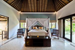 een slaapkamer met een groot bed met een baldakijn bij Villa Dihati in Tabanan