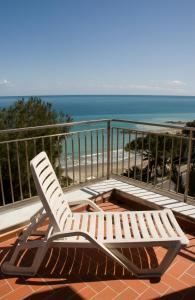 a white lounge chair sitting on a balcony overlooking the beach at Hotel Ambassador in Laigueglia