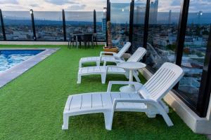 un groupe de chaises et de tables blanches sur un toit dans l'établissement Hotel Real Plaza Aguascalientes, à Aguascalientes