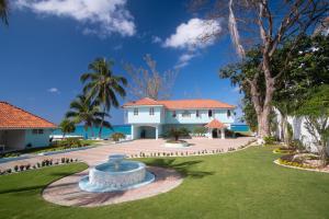 a large white house with a fountain in the yard at Edgewater Beach Villa - Beach Front, Close to All Attractions in St Mary