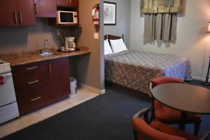 a small room with a bed and a table and a kitchen at Hope Inn and Suites in Hope