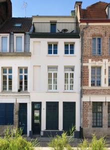 een wit huis met groene deuren en een bakstenen gebouw bij LITTLE PLAZA Appart'Hotel in Lille